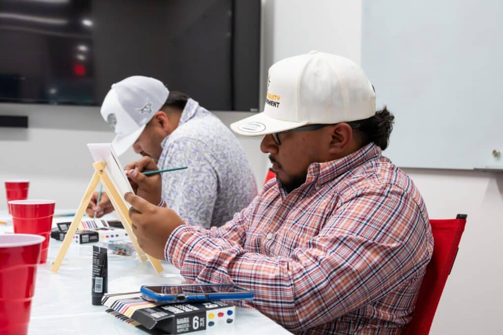 Construction team member painting on canvas during workplace mental health awareness activity