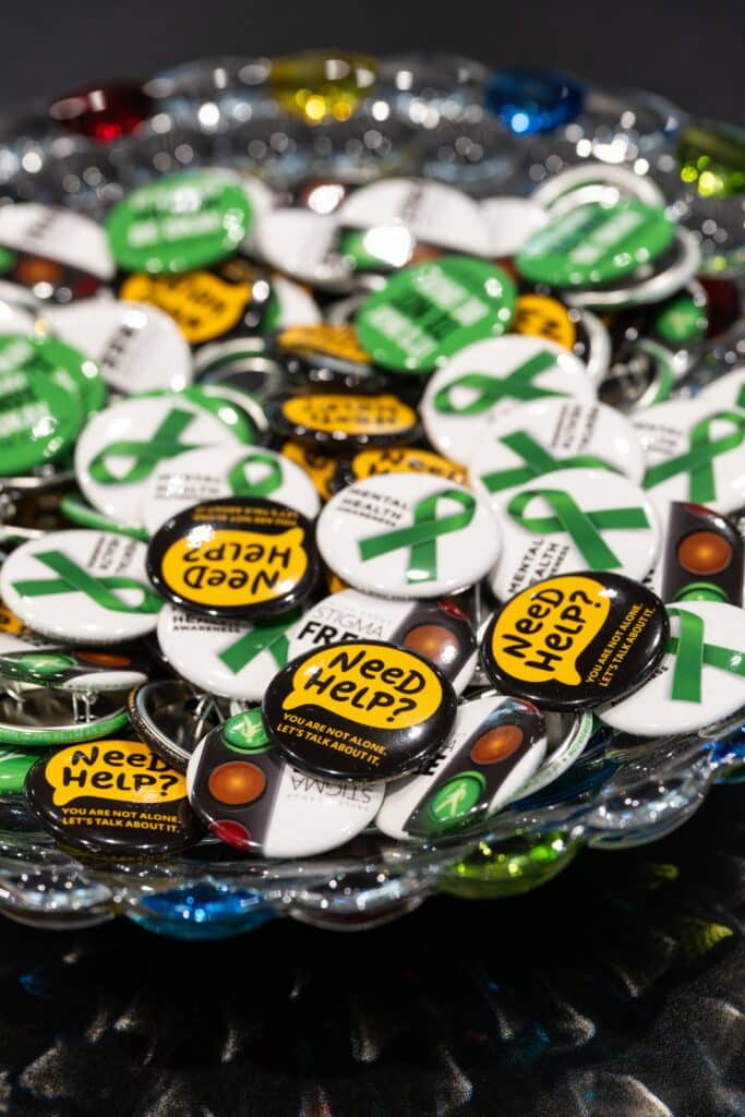 Mental health awareness buttons and green ribbon pins displayed during construction company wellness event
