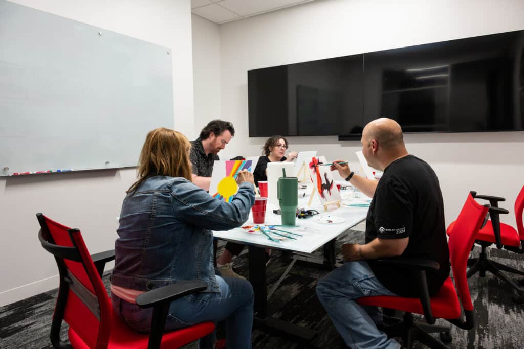 employees painting together workplace team building mental health awareness